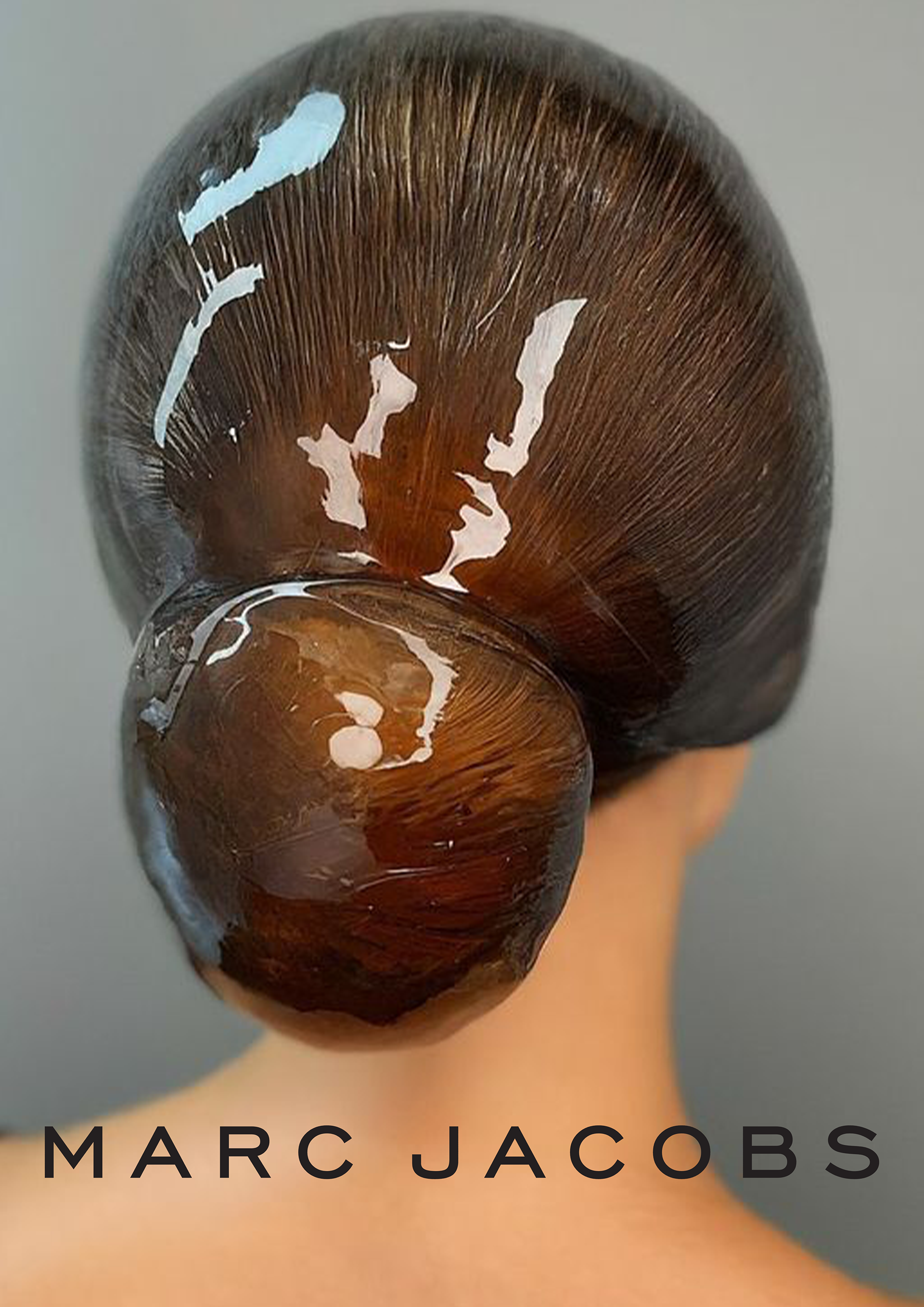 Close-up view from behind of slicked-back brown hair styled into a glossy sculpted low bun above Marc Jacobs text.