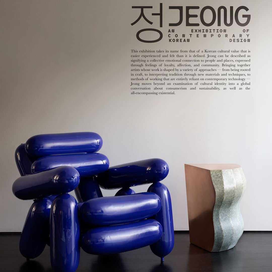 Contemporary Korean design exhibition featuring a unique blue chair and geometric side table against a minimalist wall.