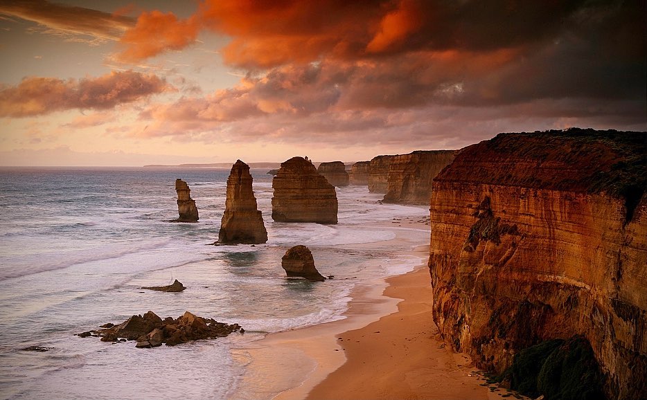 Scenic view of the Twelve Apostles rock formations along the Great Ocean Road in Victoria, Australia, with a vibrant sunset sky.