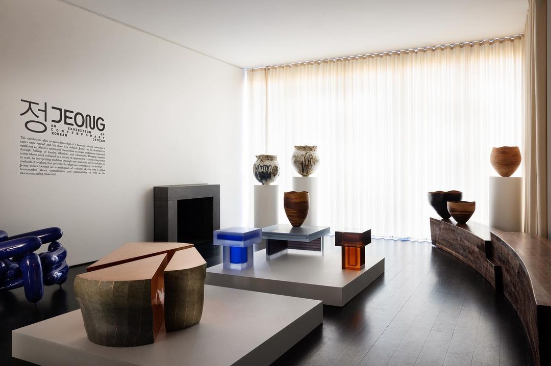 Contemporary art gallery exhibit with curated collection of vases and sculptural furniture, displayed in bright modern interior space.
