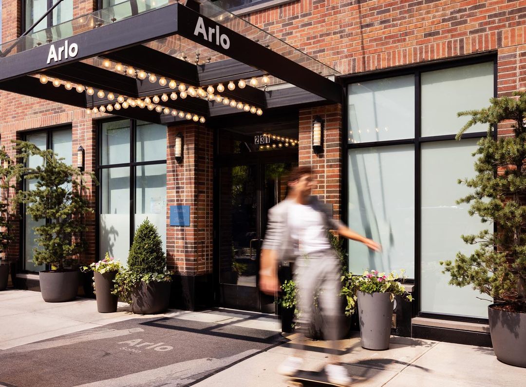 Motion blur of a person skateboarding in front of the brick entrance canopy of the Arlo hotel by photographer Nina Choi