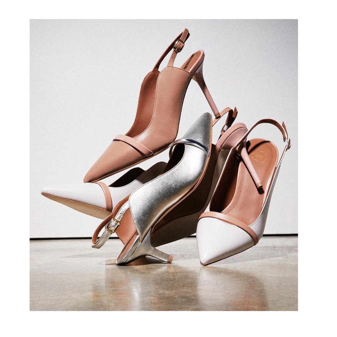 Elegant slingback heel shoes in nude, silver and white leather on a glossy floor. Fashionable women's formal footwear in a studio setting.