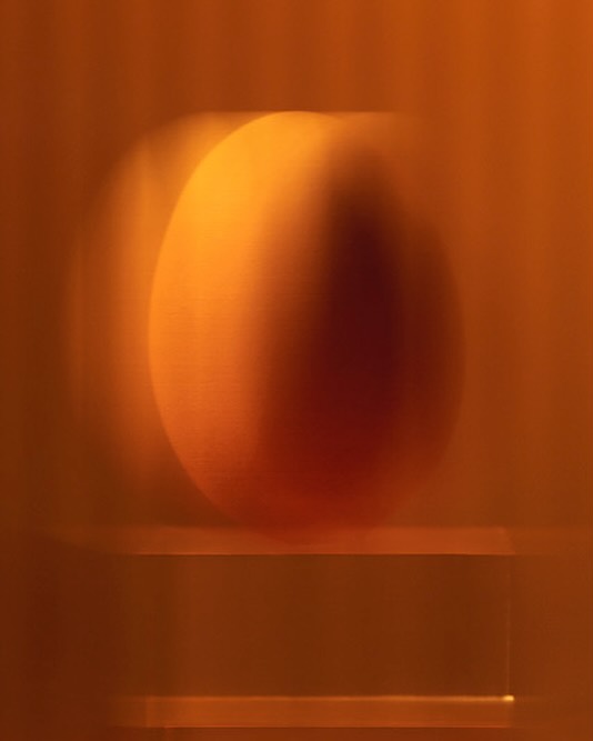 Abstract blurred image in shades of orange and brown with a diffused round shape above a rectangular form.