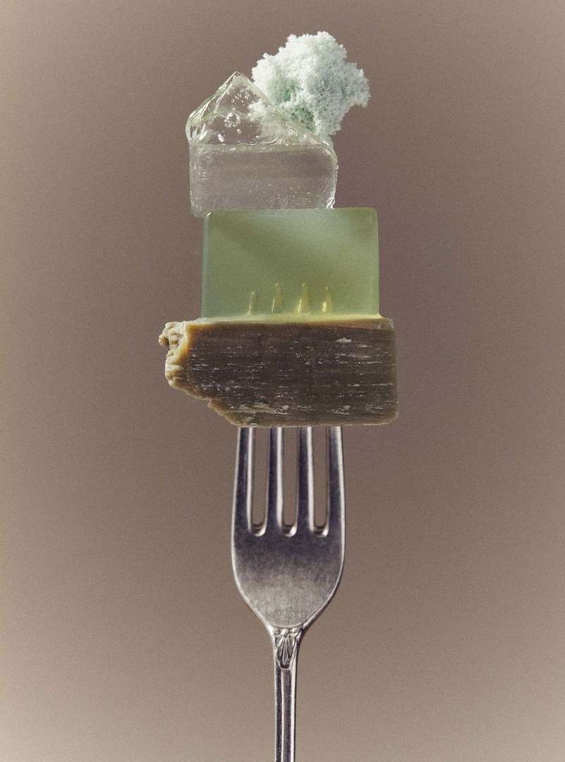 Still life of mineral specimens including quartz and calcite samples balanced on a silver fork against a neutral-toned background.