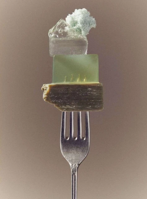 Still life of mineral specimens including quartz and calcite samples balanced on a silver fork against a neutral-toned background.