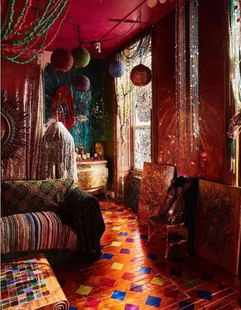 Bohemian style interior with patterned couch, colorful beads hanging from ceiling, mosaic floor, and artistic wall decor.