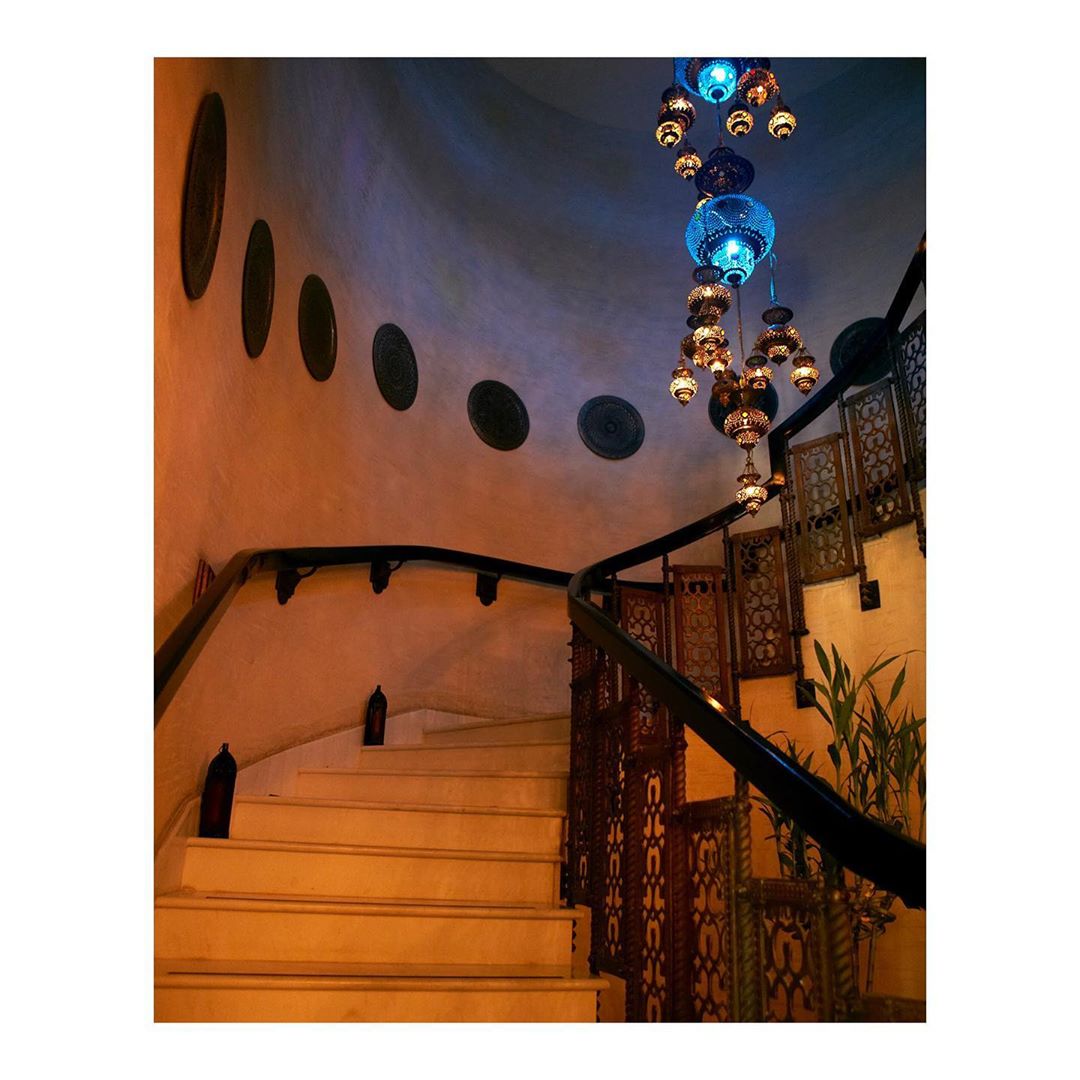 Ornate interior design with a winding staircase, dark wood railing, and decorative hanging lights in a warm color palette and soft light.