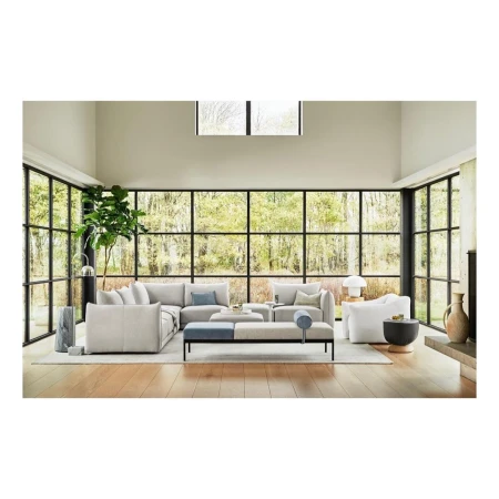 Contemporary living room interior with a large sectional sofa, bench seating, floor-to-ceiling windows, and natural light.