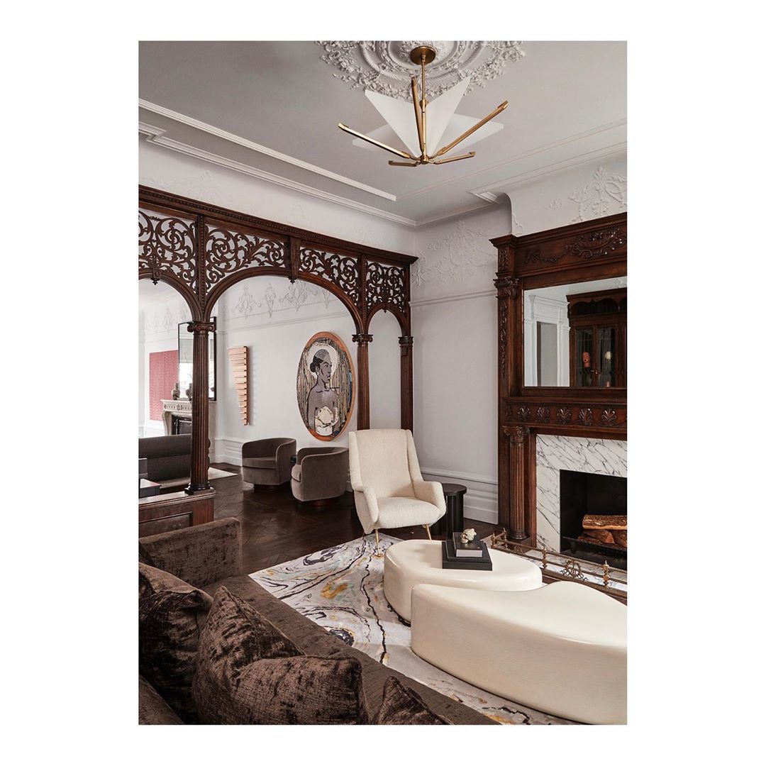 Luxurious living room interior featuring a brown velvet sofa, cream-colored seating, ornate woodwork, decorative fireplace, and modern lighting.