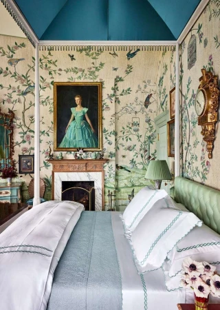 Opulent bedroom interior with four-poster bed, floral wallpaper, antique clock, painting of a woman, and marble fireplace.
