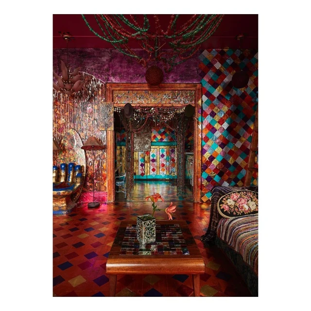 Opulent interior of a colorful room showcasing a vibrant mix of textures, patterns, and decorative elements in a home setting.