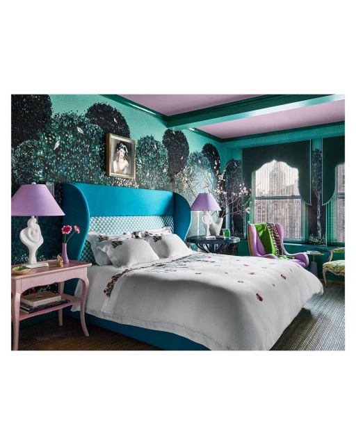 Interior bedroom design featuring a large bed with floral bedding, turquoise headboard, floral wallpaper, and a pink bedside table with a lamp.