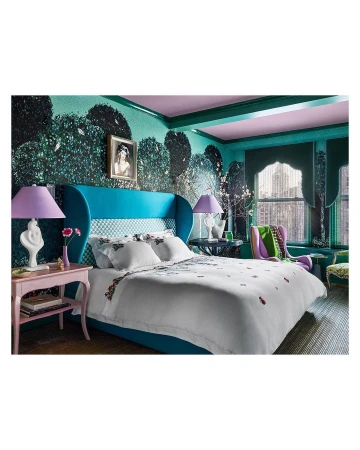 Interior bedroom design featuring a large bed with floral bedding, turquoise headboard, floral wallpaper, and a pink bedside table with a lamp.