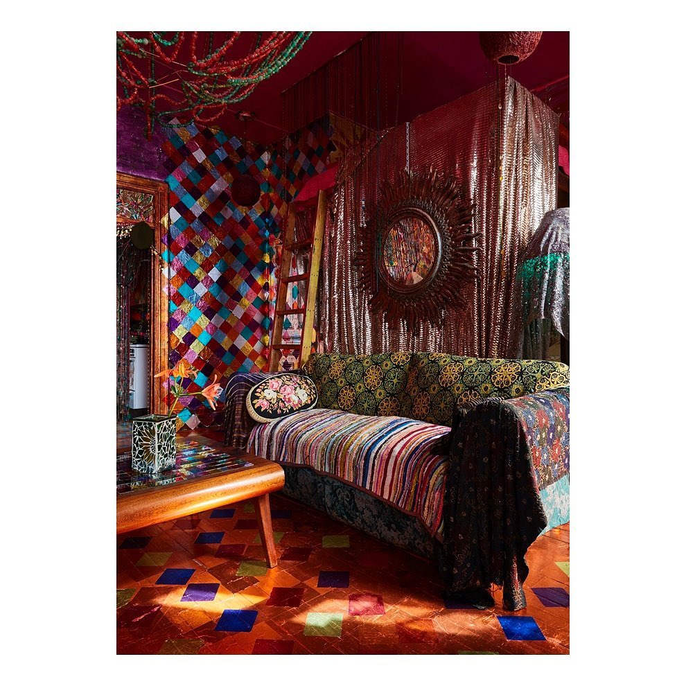 Eclectic living room interior with a patterned sofa, colorful walls, a decorative mirror, and a tiled floor in warm, inviting tones.