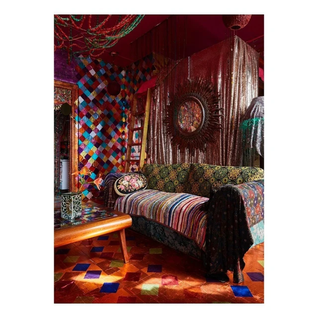 Eclectic living room interior with a patterned sofa, colorful walls, a decorative mirror, and a tiled floor in warm, inviting tones.