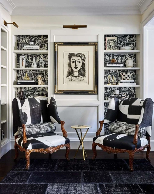 Interior design with two black-and-white patterned armchairs, a side table, and a wall unit with shelves and artwork in a home setting.