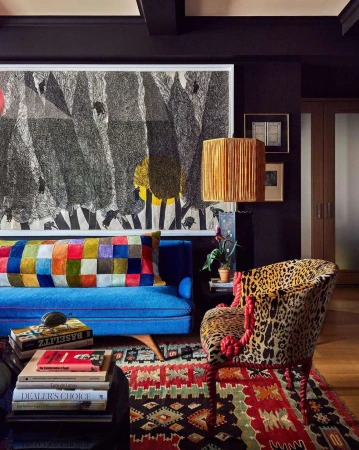 Eclectic living room interior with a bright blue sofa, leopard print armchair, patterned rug, and large abstract art on dark walls.