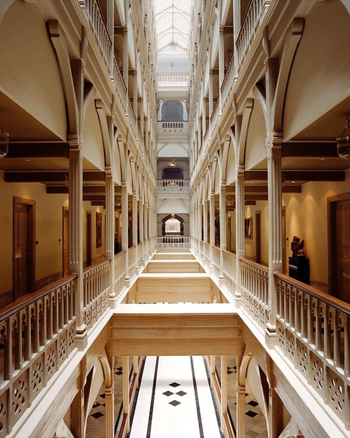 Interior architecture showing multiple floors and arched columns of an indoor hallway with decorative railings and a skylight above.