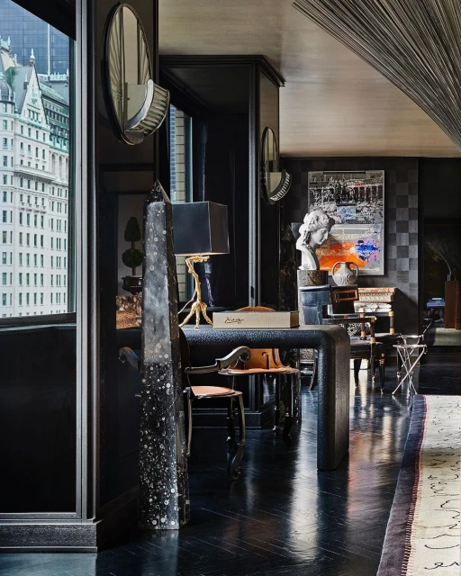 Elegant interior featuring modern furnishings, a textured desk, and a view of a city skyline through a large window.