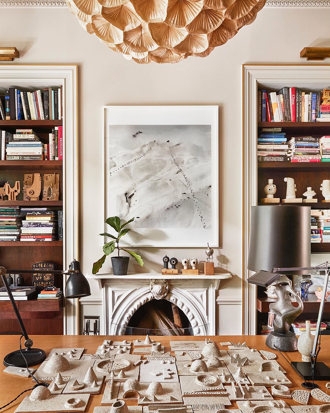 Interior view of a room featuring a desk with miniature landscape models, built-in bookshelves, and a decorative ceiling light.