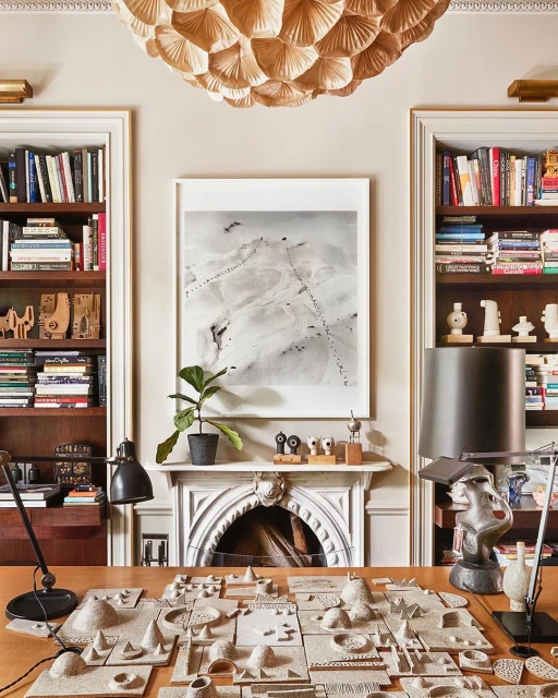 Interior view of a room featuring a desk with miniature landscape models, built-in bookshelves, and a decorative ceiling light.