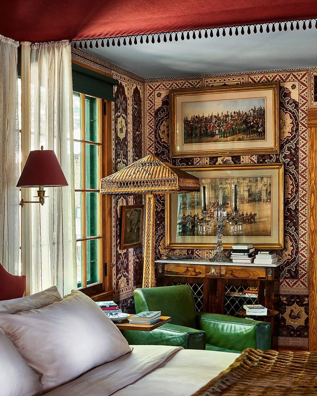 Ornate bedroom interior featuring a bed, lamps, wall art, and patterned walls and ceiling, creating a visually rich, traditional aesthetic.