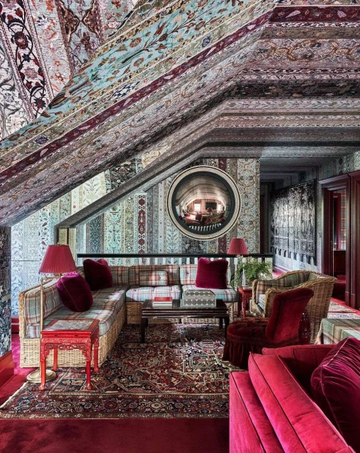 Ornate interior with patterned walls and ceiling, featuring a wicker sofa, coffee table, and rug, creating a visually rich home setting.
