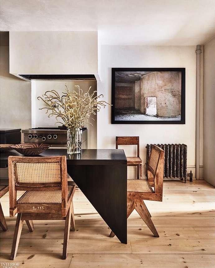 Dining area interior featuring a wooden table, four chairs, vase with decorative branches, and a framed photograph on the wall.
