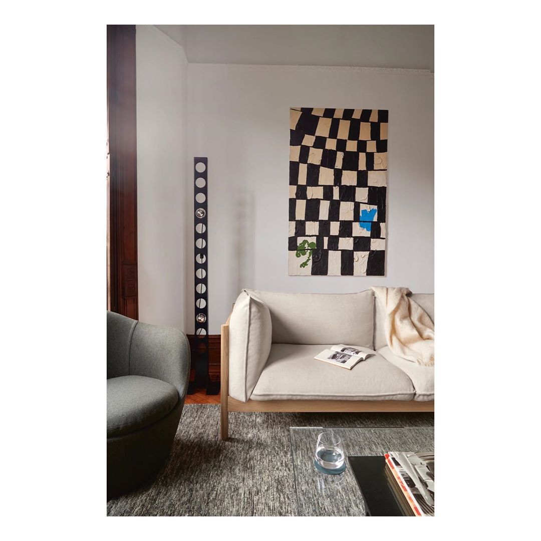 Living room interior featuring a cream-colored sofa, patterned rug, artwork, and modern decor elements creating a stylish and cozy atmosphere.