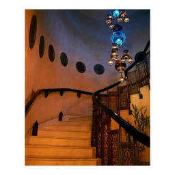Curved staircase with ornate black railing, illuminated by an intricate multi-globe pendant lamp hanging above.