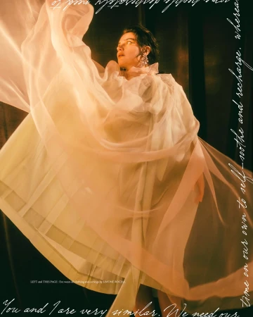 Woman in elegant white dress with sheer fabric, captured in a portrait with soft lighting and dark background for fashion editorial.