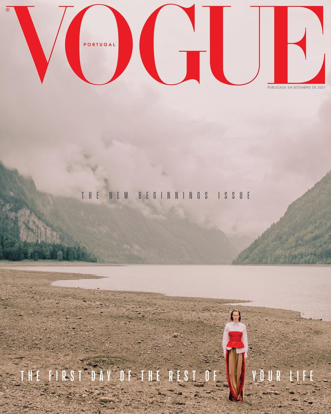 Vogue Portugal cover featuring a woman standing on a rocky shore with a lake and mountains in the background, under the 'New Beginnings' theme.