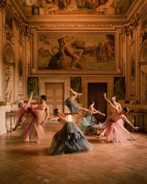 Group of ballet dancers in ornate studio, performing in tulle skirts. Classical paintings on the wall with marble flooring.