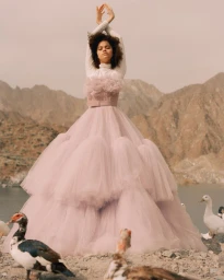 Model in voluminous pink tulle gown posing near water and mountains with ducks in foreground by Noemi Ottilia Szabo