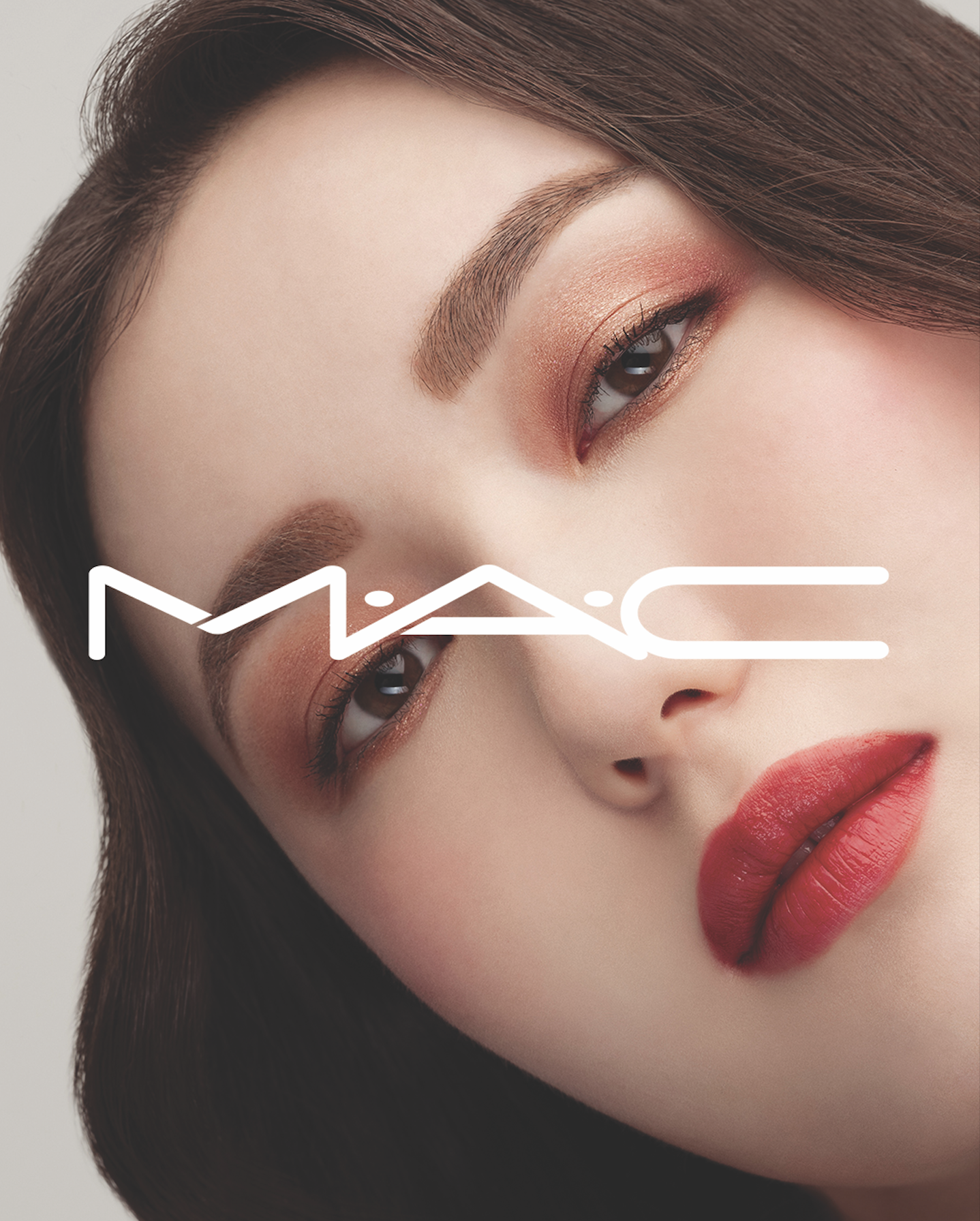 Close-up of a person with warm-toned eyeshadow and bold red lipstick with a white MAC cosmetics logo overlaid on the image.