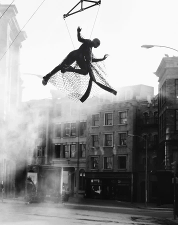 A black-and-white photo of a floating human figure suspended above a city street amid a misty atmosphere, creating a surreal effect.