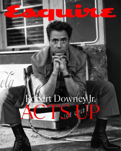 Black and white portrait of Robert Downey Jr. seated with clasped hands, in front of a vintage Coca-Cola cooler, for Esquire magazine cover.