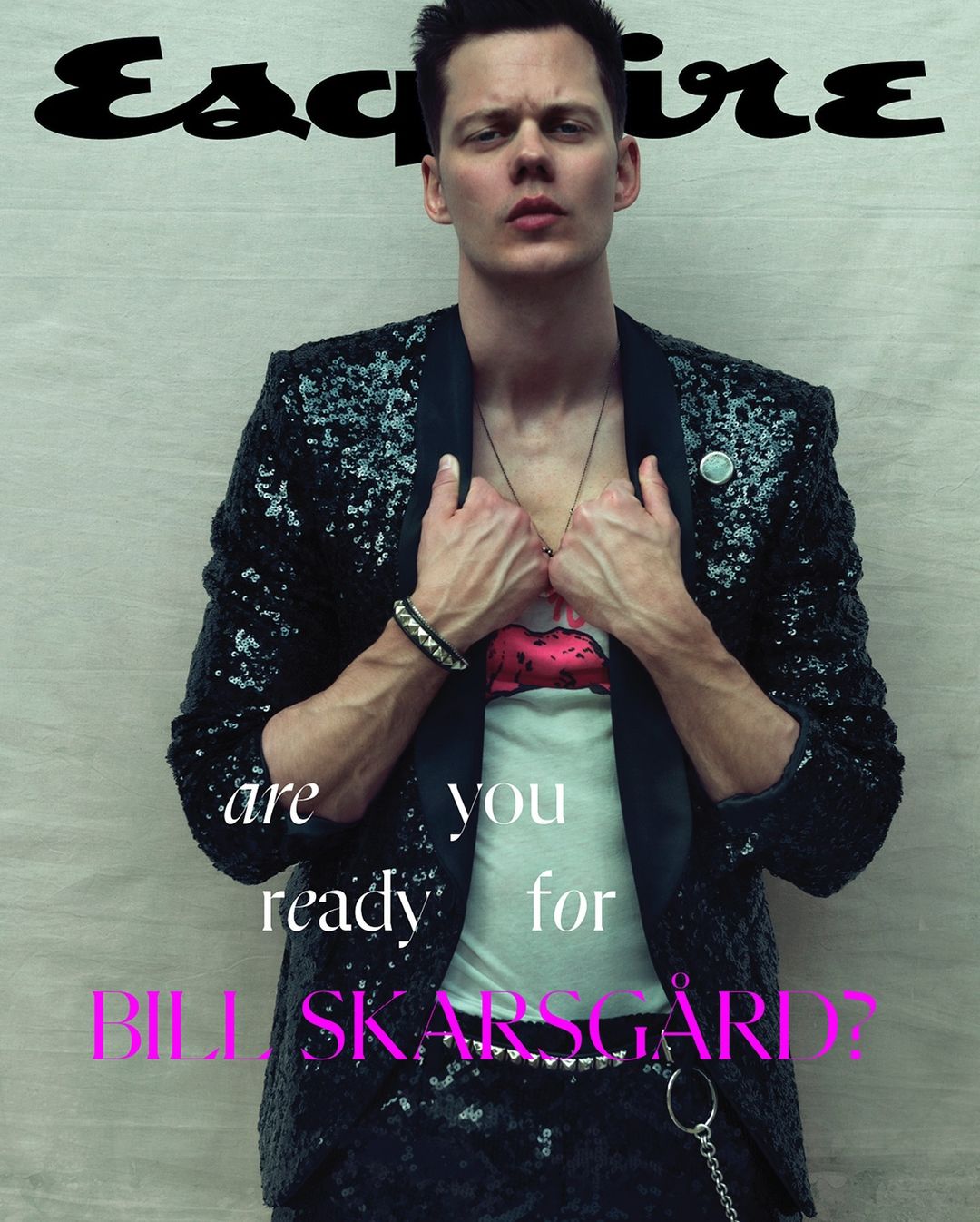 Esquire magazine cover featuring Bill Skarsgard in a sequined jacket, graphic tee, and black pants, standing indoors with logo text.