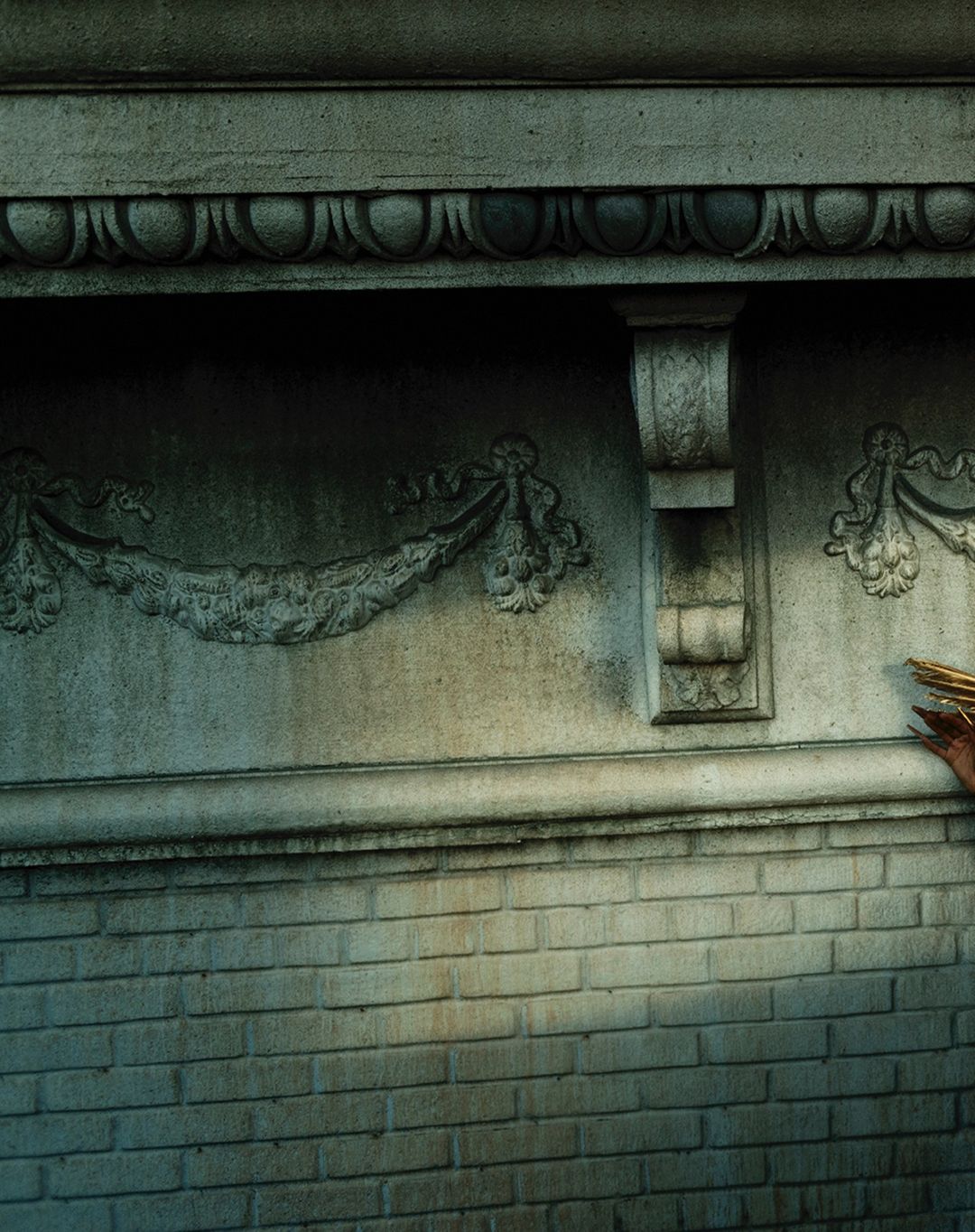 Detailed stone wall with carved architectural details, including garlands and moldings, showcasing masonry and craftsmanship.