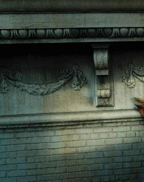 Detailed stone wall with carved architectural details, including garlands and moldings, showcasing masonry and craftsmanship.