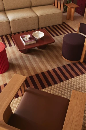 High-angle view of a modern living room interior with a beige sectional sofa, striped area rugs, and a low red coffee table.