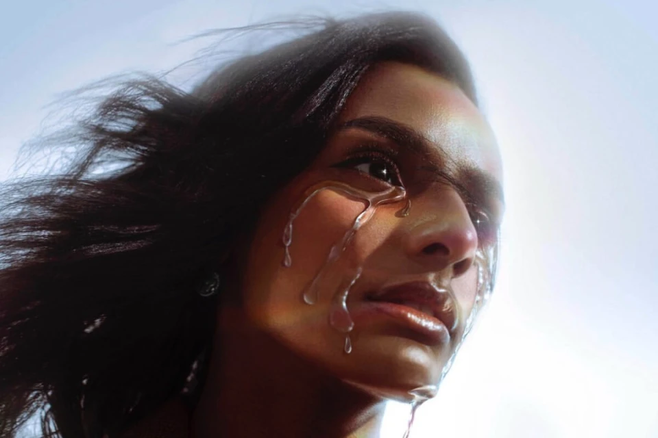 Close-up portrait of a woman with liquid dripping down her face, creating a glossy, textured effect against a bright sky background.
