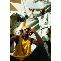 Group of young models in streetwear with bucket hats and sunglasses posing against a draped fabric backdrop in Paris by Ojoz