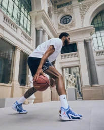 A man dribbling a basketball inside a grand hall with neoclassical architecture in Paris, photographed by Ojoz.