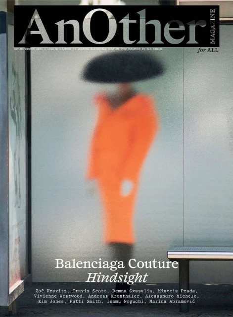 Fashion magazine cover featuring blurred figure in orange against a frosted glass background with visible publication and brand typography.