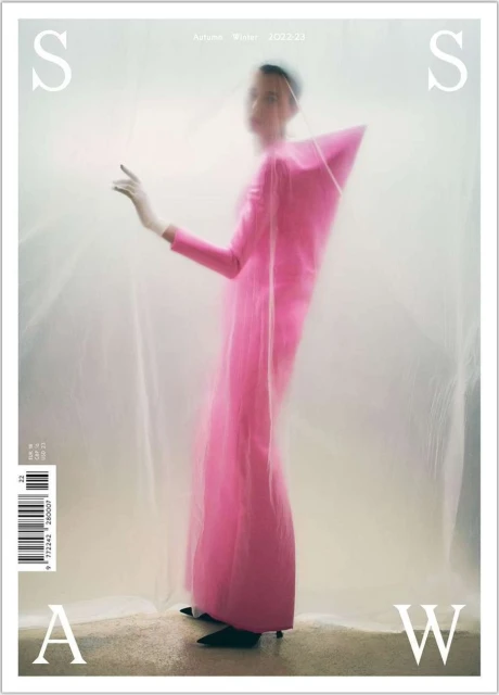 Fashion editorial cover featuring a slender woman in a pink gown with avant-garde tailoring, posing against a blurred light background.