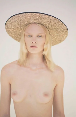 Model wearing a wide-brimmed metallic hat against a plain light background in a portrait by Ola Rindal