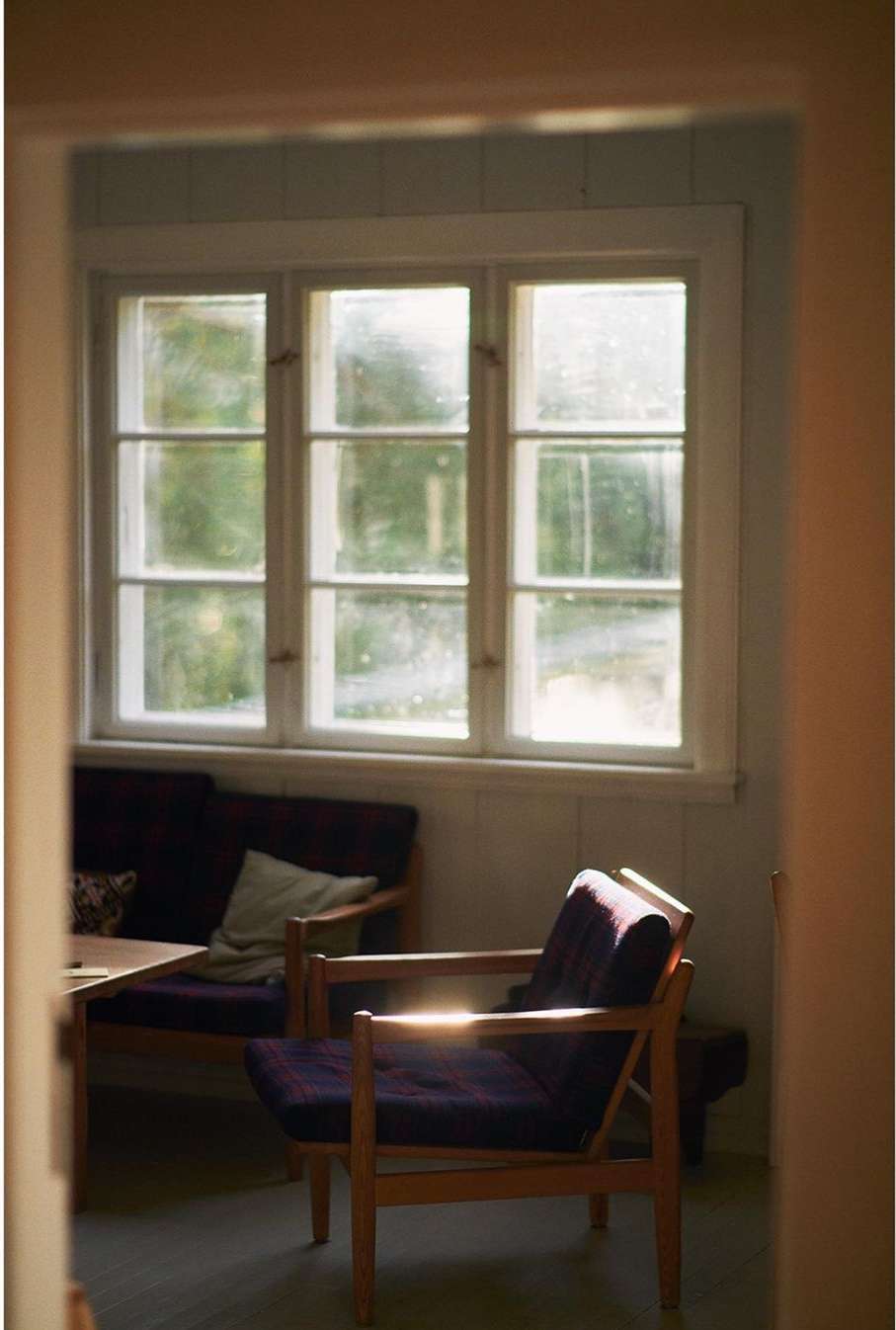 Interior view of a living room with a purple armchair, sofa, a coffee table, and a large window providing natural light.