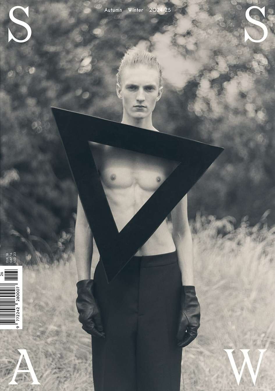 Magazine cover featuring a bare-chested man in black pants and gloves, posing with a triangle frame in an outdoor setting.