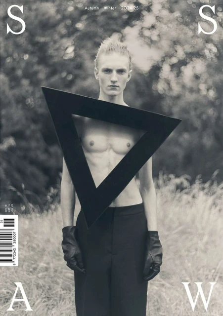 Magazine cover featuring a bare-chested man in black pants and gloves, posing with a triangle frame in an outdoor setting.